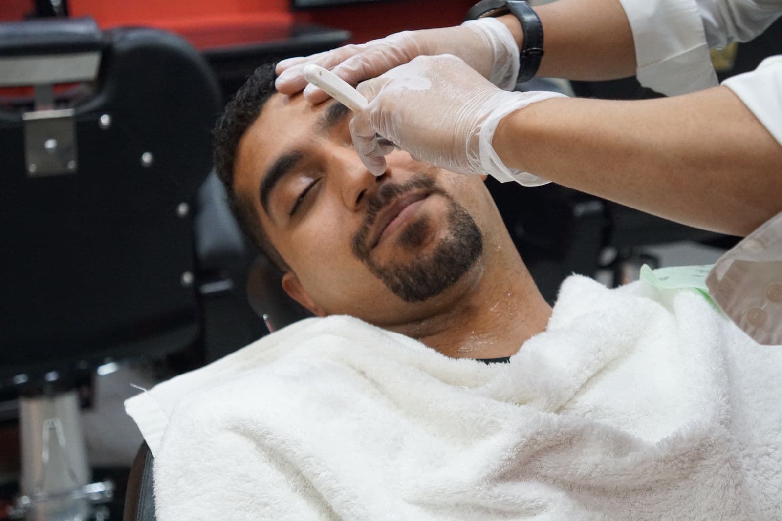 A steaming hot towel wrapped over a client's face before the shave