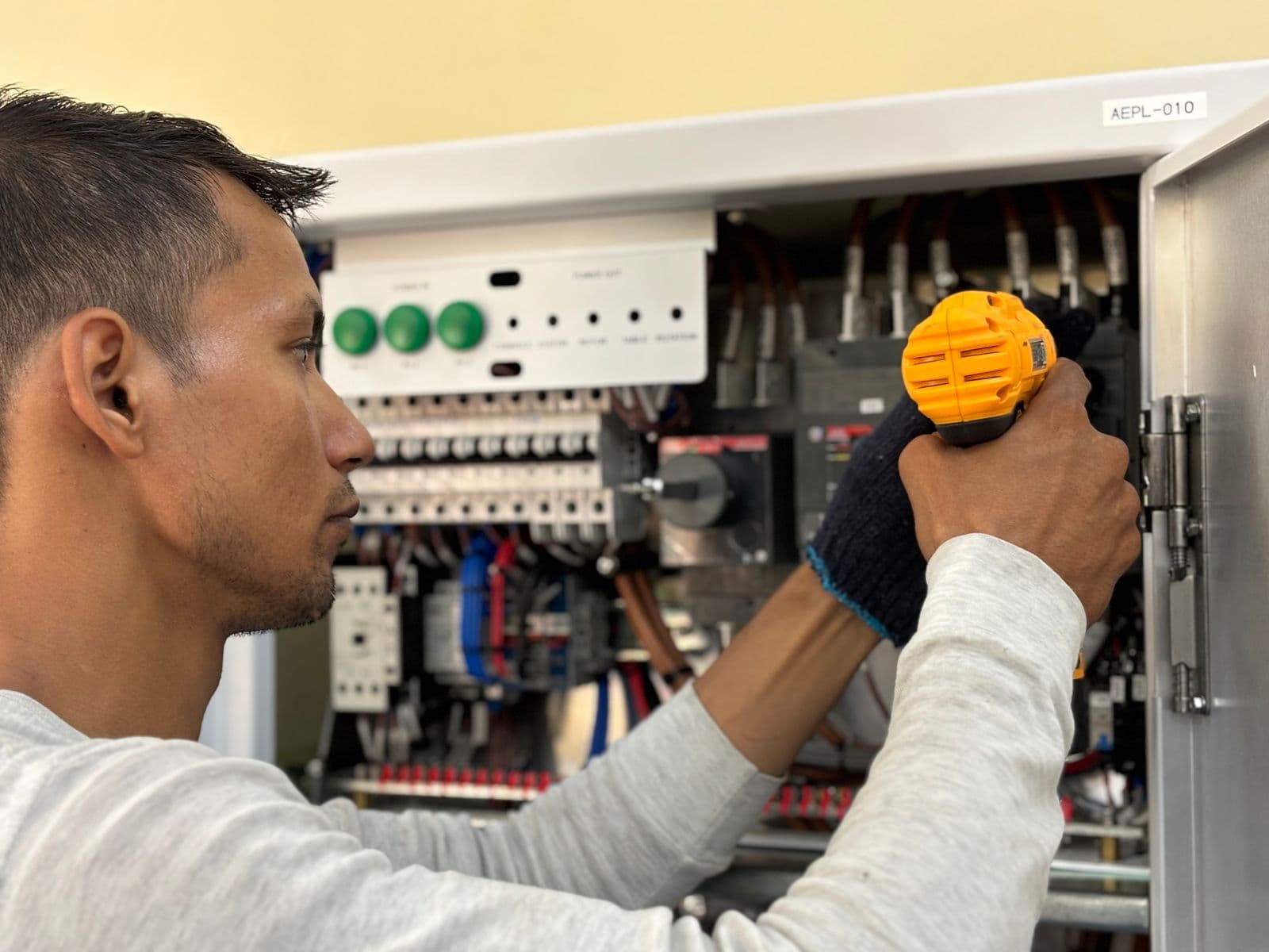 Electrician using a tool inside an open breaker panel