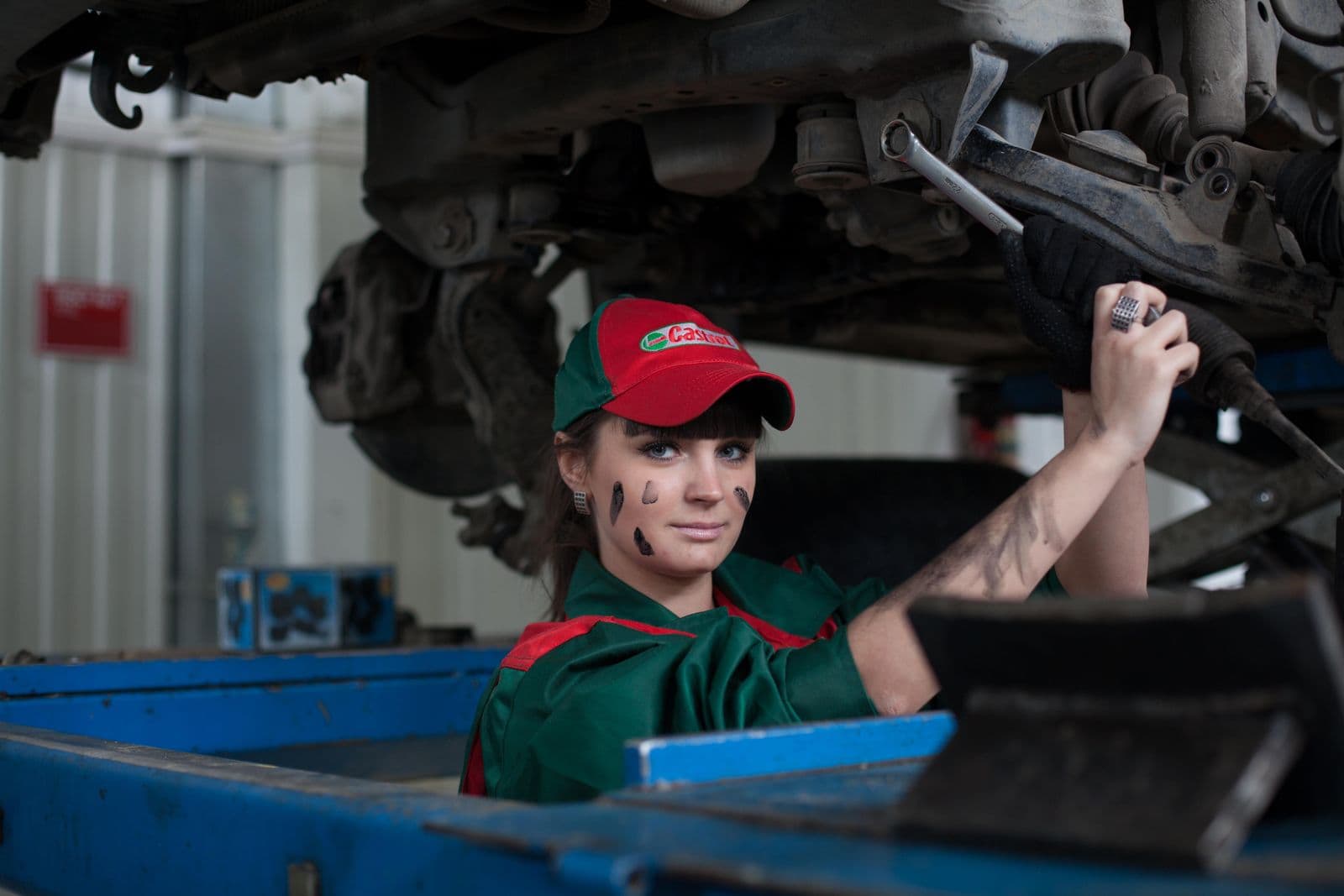 Technician working beneath a vehicle raised on a lift while the transmission is out for rebuild