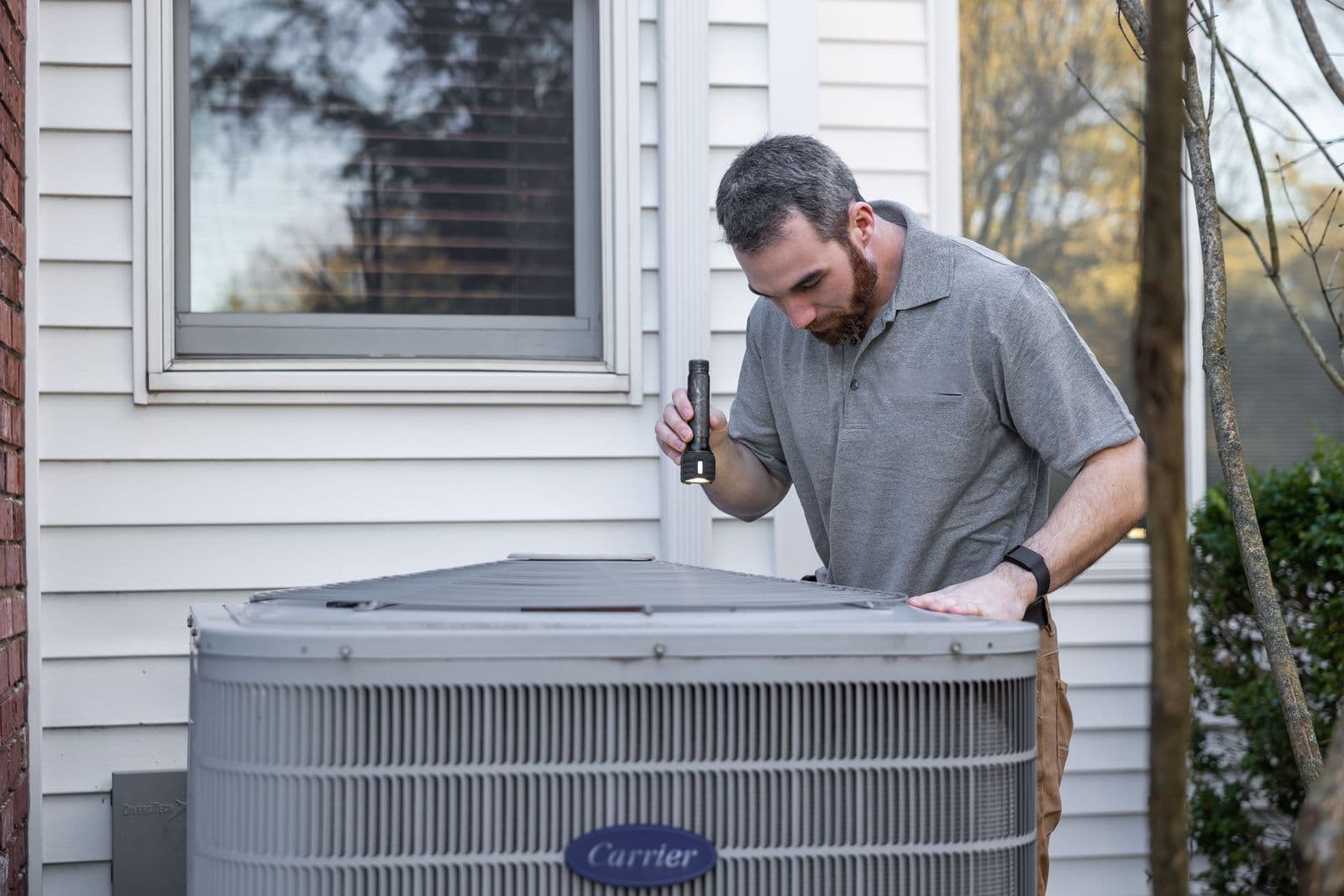 TwinSeason technician servicing an outdoor AC condenser on a hot day