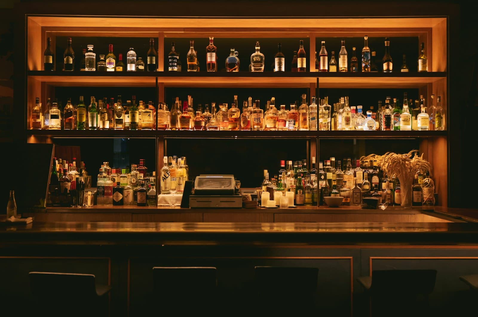 The Oak & Ember back bar, bottles lit low and warm