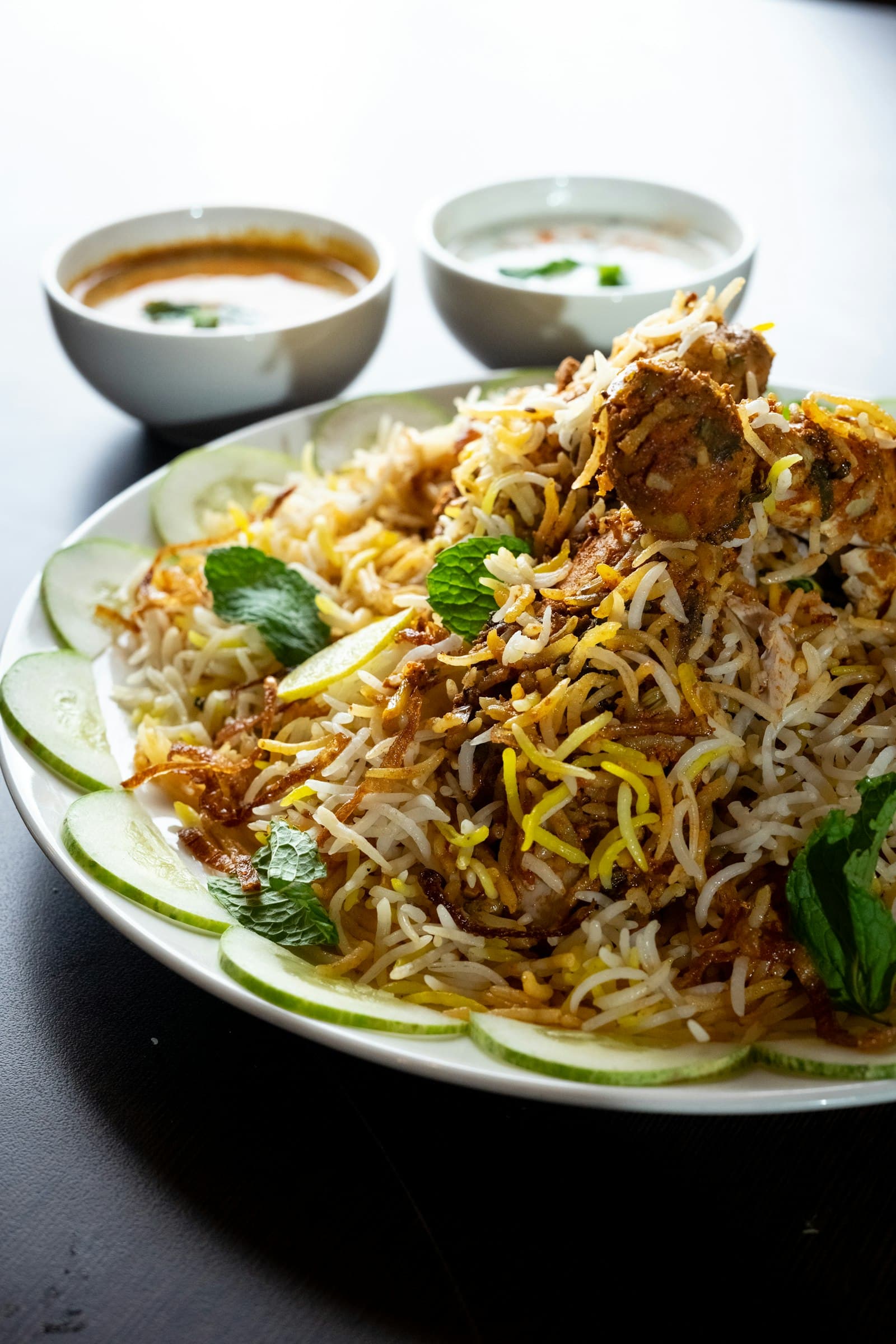 Serving dish of saffron chicken biryani with fried onions
