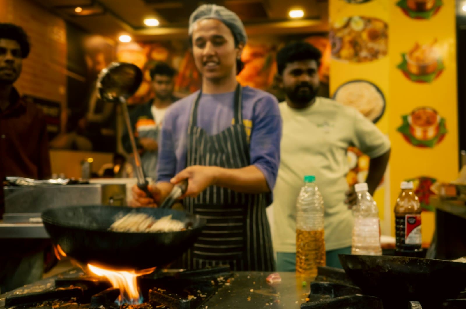 Cook tossing noodles over a flaming street-side wok